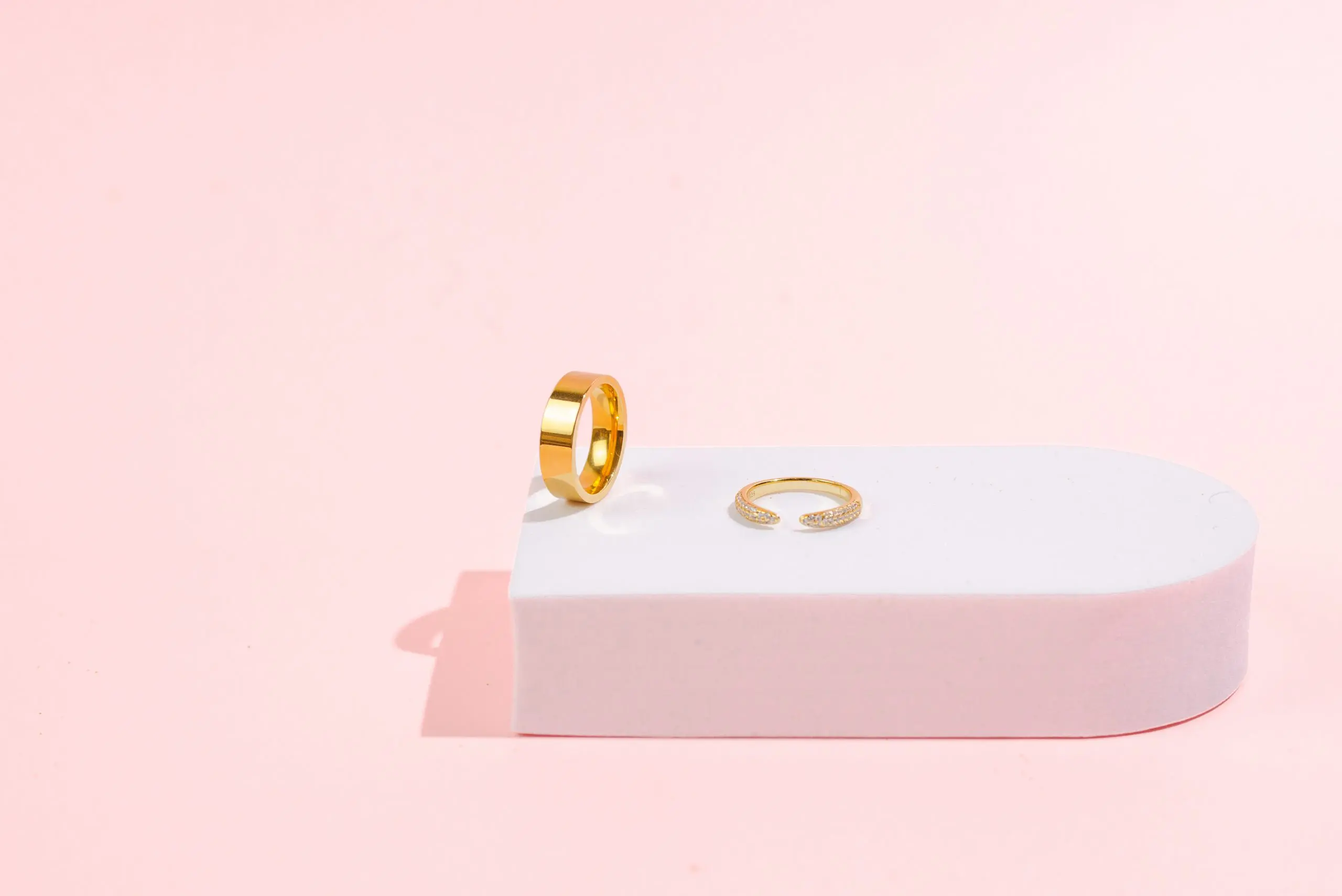 still like jewelery product photography services by danielle deangelis. gold rings photographed on a pink background with a white riser